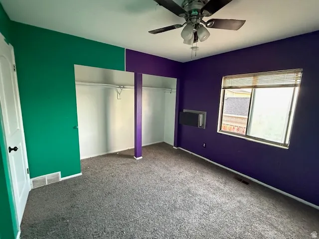 Room featuring two tone wall colors, a ceiling fan, a window with blinds, and built-in closet spaces