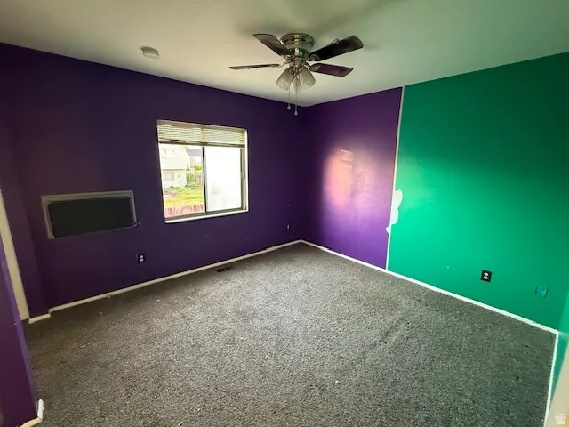 Interior room featuring grey carpeting, a multi-pane window, and a ceiling fan with light fixture