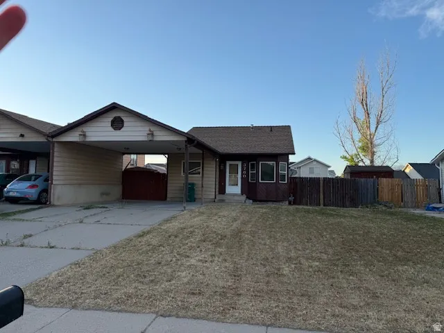 Exterior featuring an attached carport, front yard, and a fenced side yard