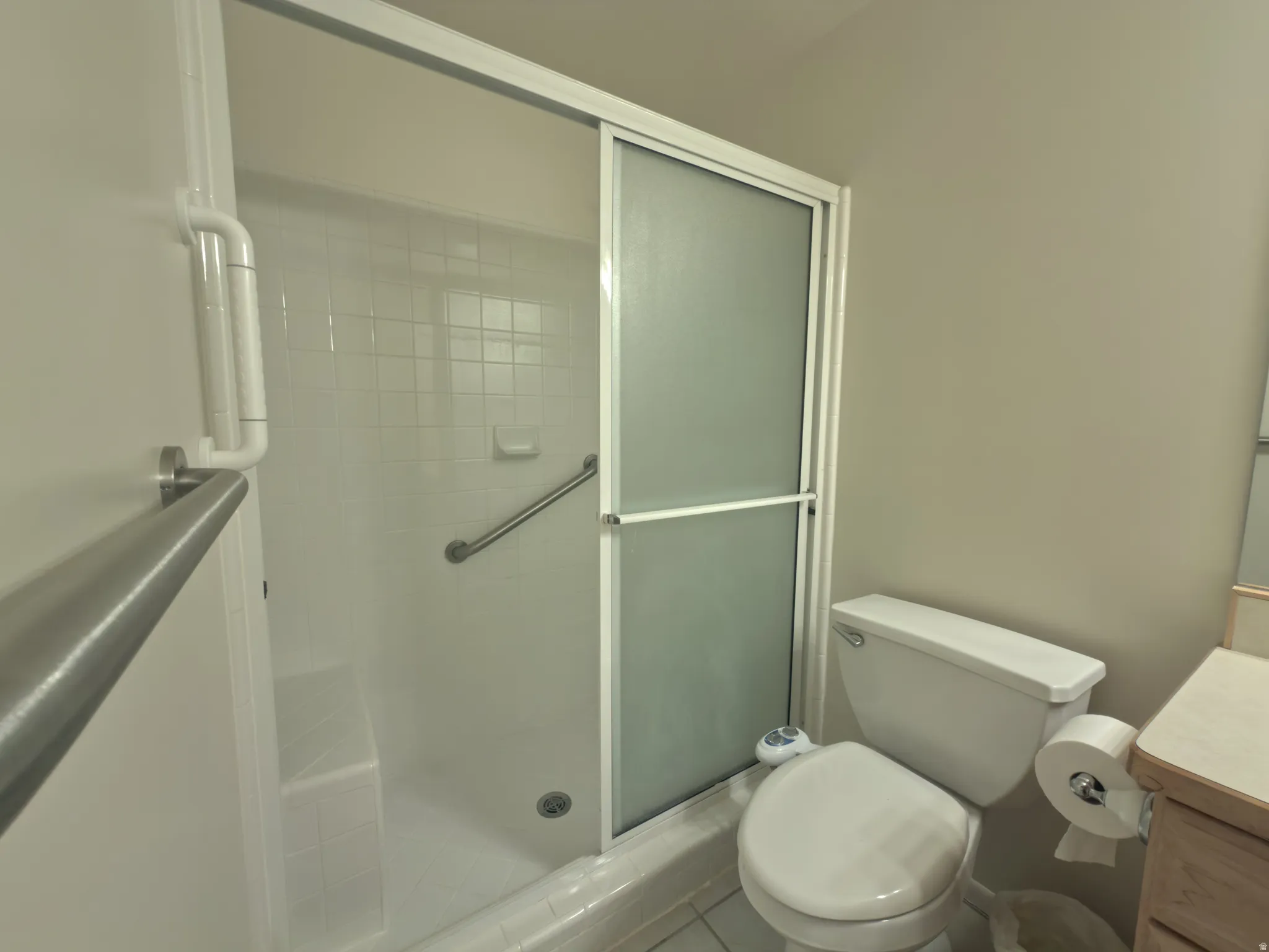 Walk-in shower with sliding frosted glass doors, integrated seating, and grab bars