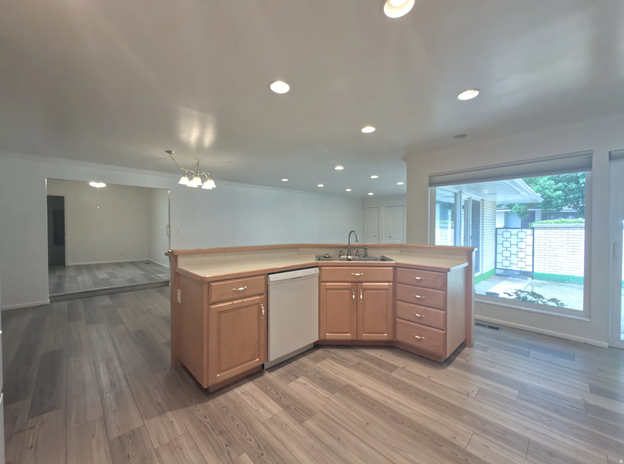 Kitchen island with light wood cabinetry and integrated sink, featuring a cream-colored countertop