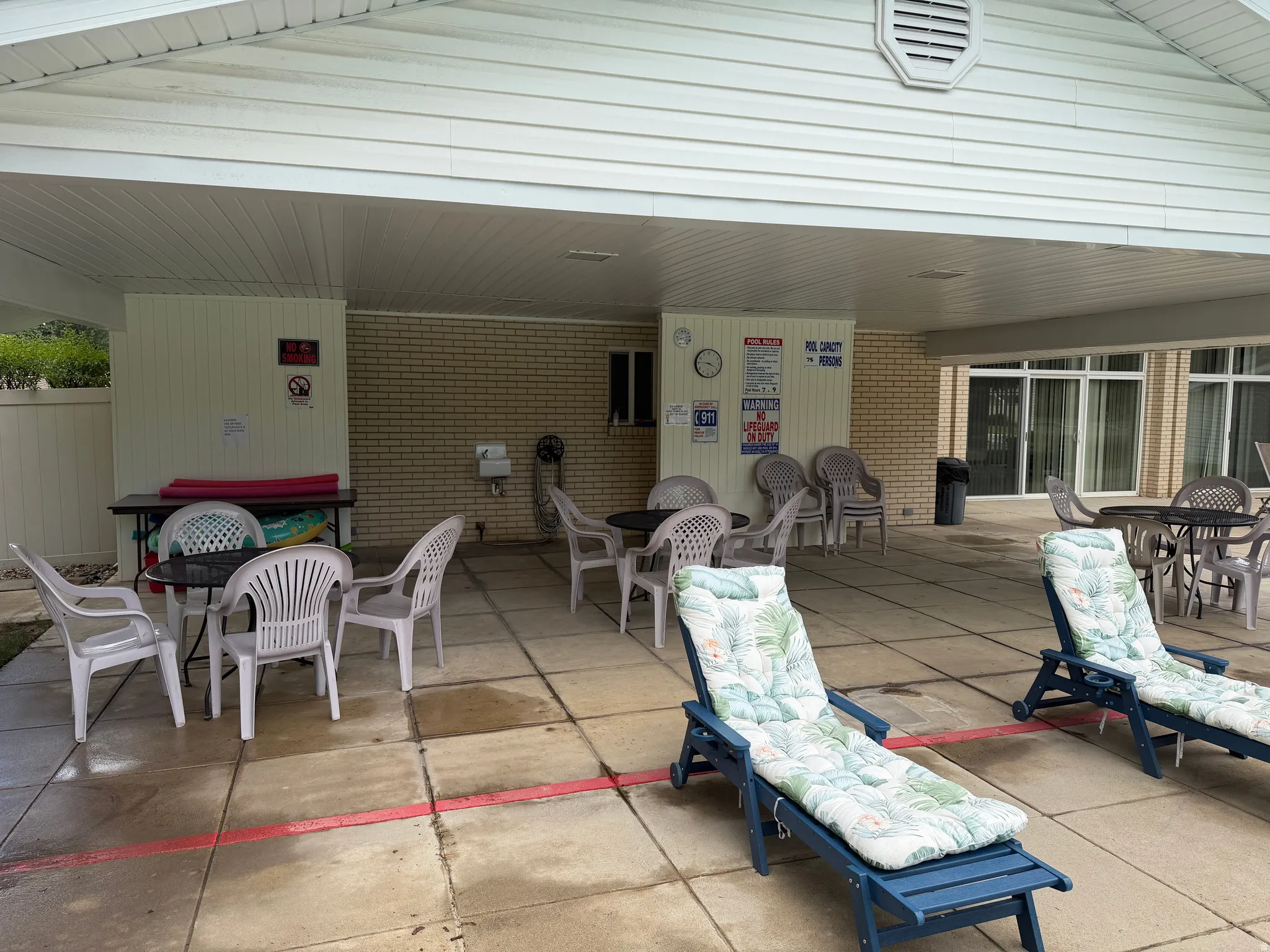 Club House Covered patio area featuring a concrete slab, white vinyl siding, and a light brick wall