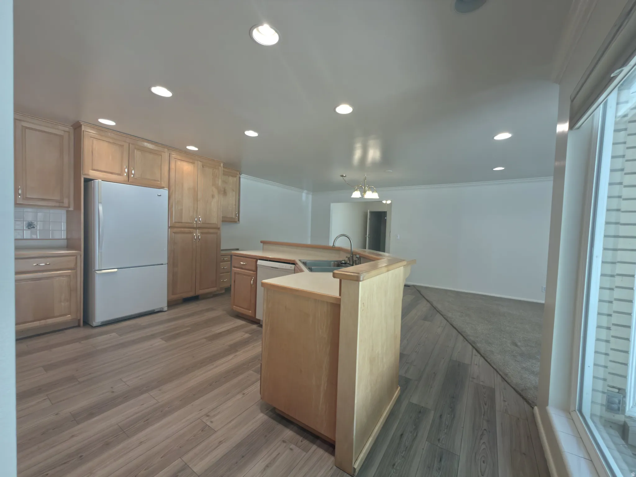 Kitchen featuring wood-finish flooring, wood cabinetry with brushed nickel hardware, and recessed lighting