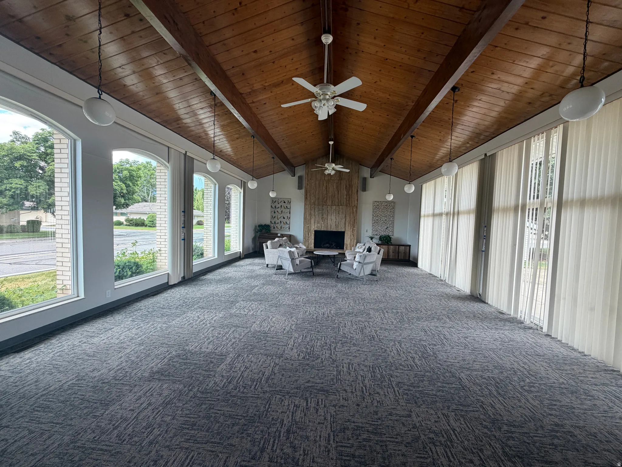 Club House Spacious room with a vaulted wood-paneled ceiling, exposed wood beams, and textured gray carpeting