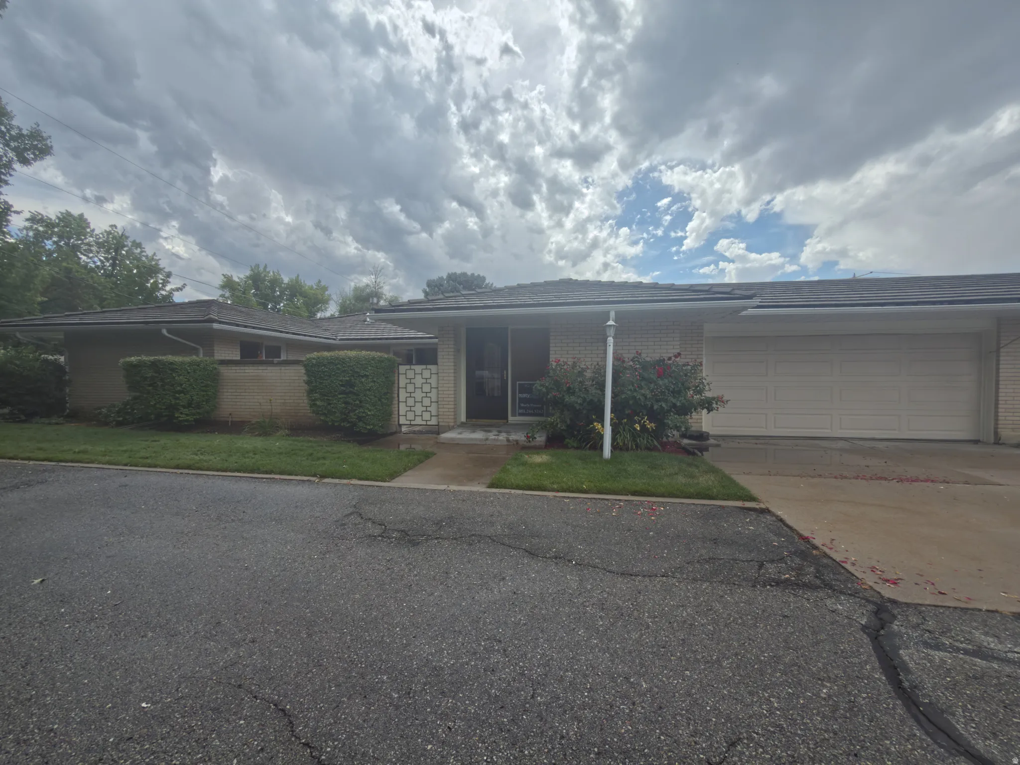 Single-story residence featuring a brick facade, attached two-car garage, and established front landscaping