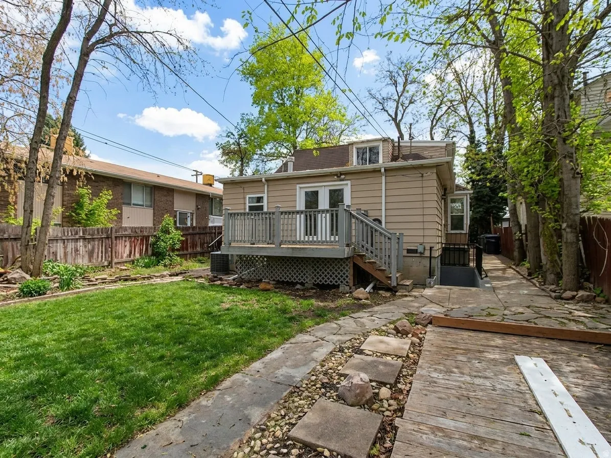 Rear exterior featuring a spacious wooden deck with railings, a dormer window, and an accessible basement entry