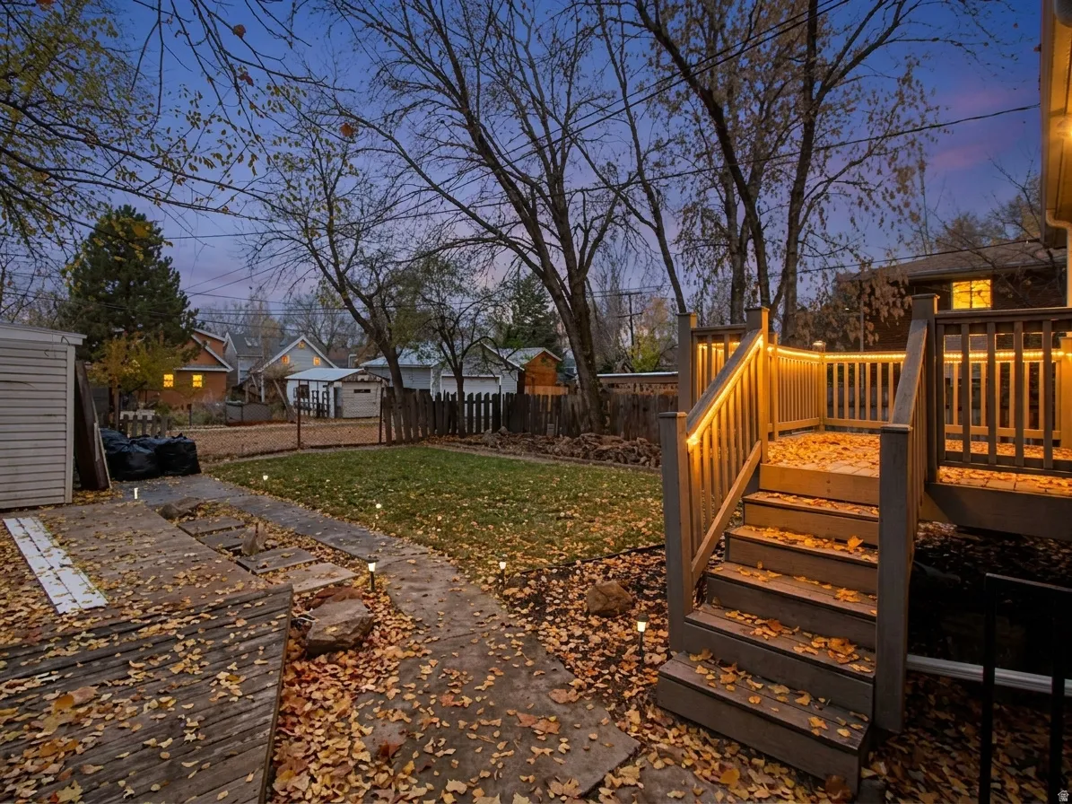 Multi-level deck with integrated lighting, wood-finish railing, and stairs descending to a concrete pathway