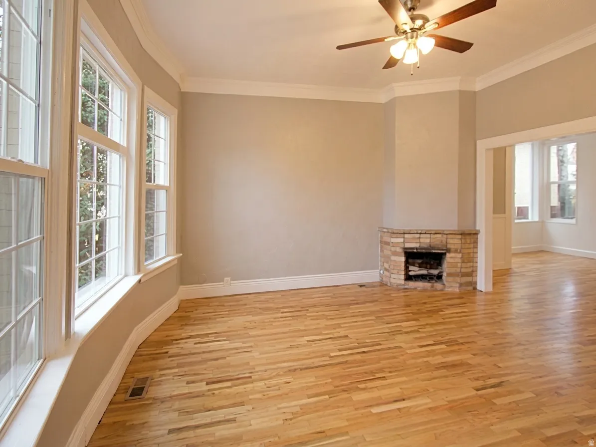 Hardwood flooring throughout featuring a corner stone fireplace