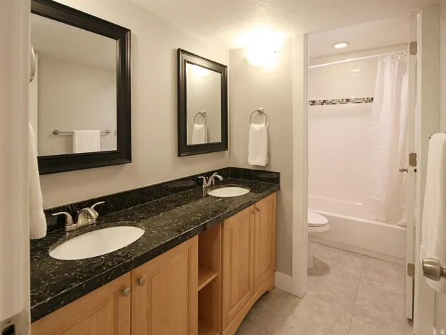 Double vanity featuring a speckled countertop, undermount sinks, and wood-finish cabinetry