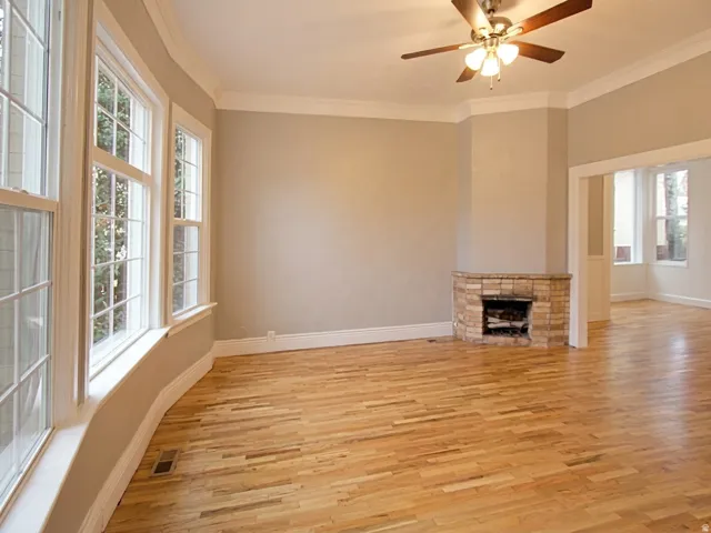 Hardwood flooring throughout featuring a corner stone fireplace