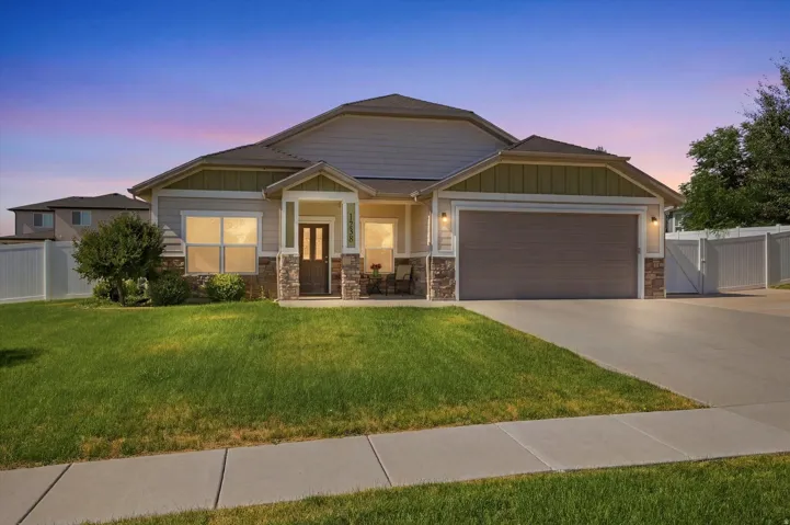 Single-story residence featuring a two-car garage, stone veneer accents, and a covered entry porch
