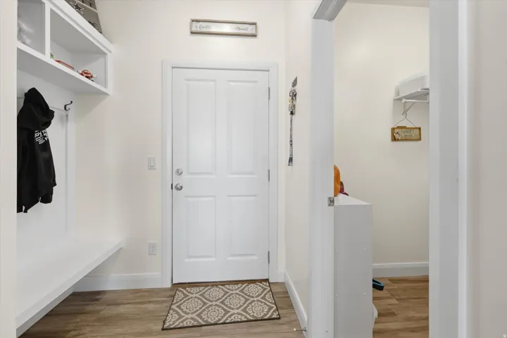 Entryway from garage with built-in white shelving and integrated coat hooks