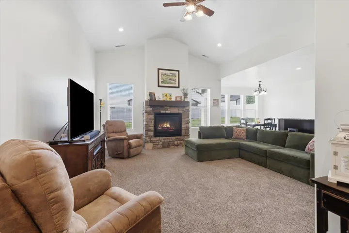 Vaulted ceiling living room featuring a stone-clad fireplace with a wood mantel
