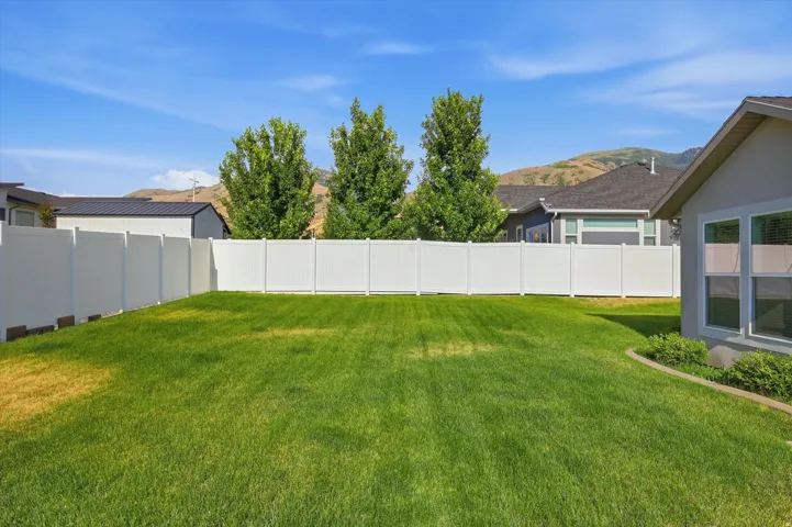 Expansive grassy yard enclosed by a white privacy fence