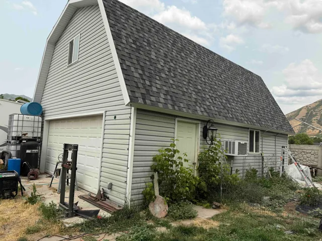 Two-story garage featuring a gambrel roof and light-colored siding