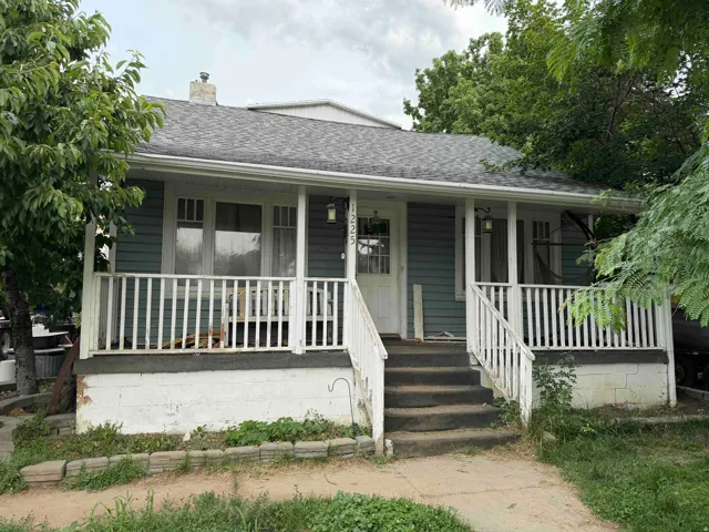 Charming bungalow featuring light blue siding, a dark gray shingle roof, and a white-railed covered porch
