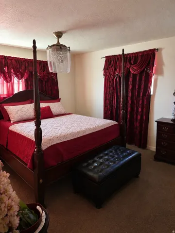 Carpeted room featuring a ceiling-mounted light fixture, and a window with curtain rod and drapes