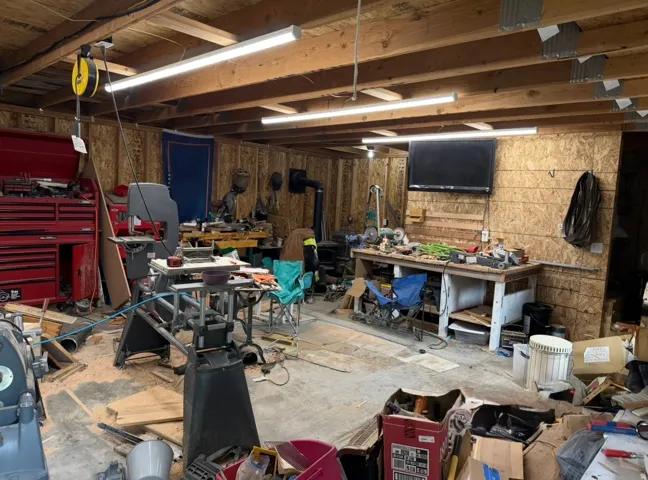 Workshop featuring overhead fluorescent lighting, workbench and a visible wood-burning stove