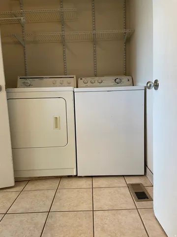 Dedicated laundry area featuring a tile floor, overhead wire shelving, and space for a washer and dryer