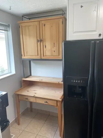 Built-in desk and storage unit featuring natural wood-finish cabinetry, black metal framing, and dual drawers