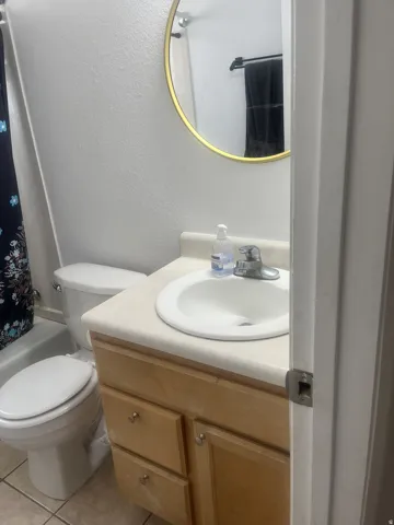 Bathroom vanity with a light wood-finish cabinet and a white countertop