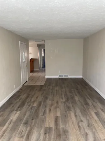 Spacious room with wood-finish flooring, light neutral wall paint, and white baseboards