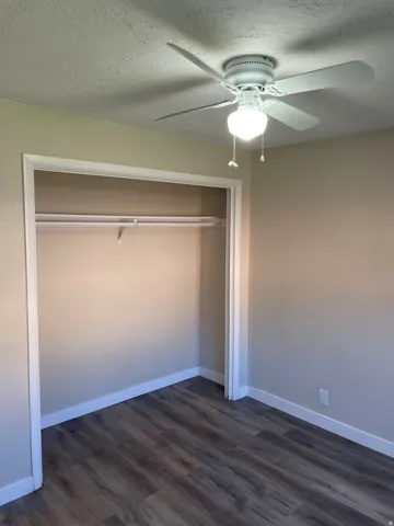 Room featuring wood-finish flooring, a built-in closet with hanging rod, and a ceiling fan with integrated lighting