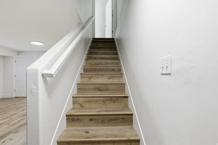 Staircase featuring wood-finish treads and risers with a white handrail