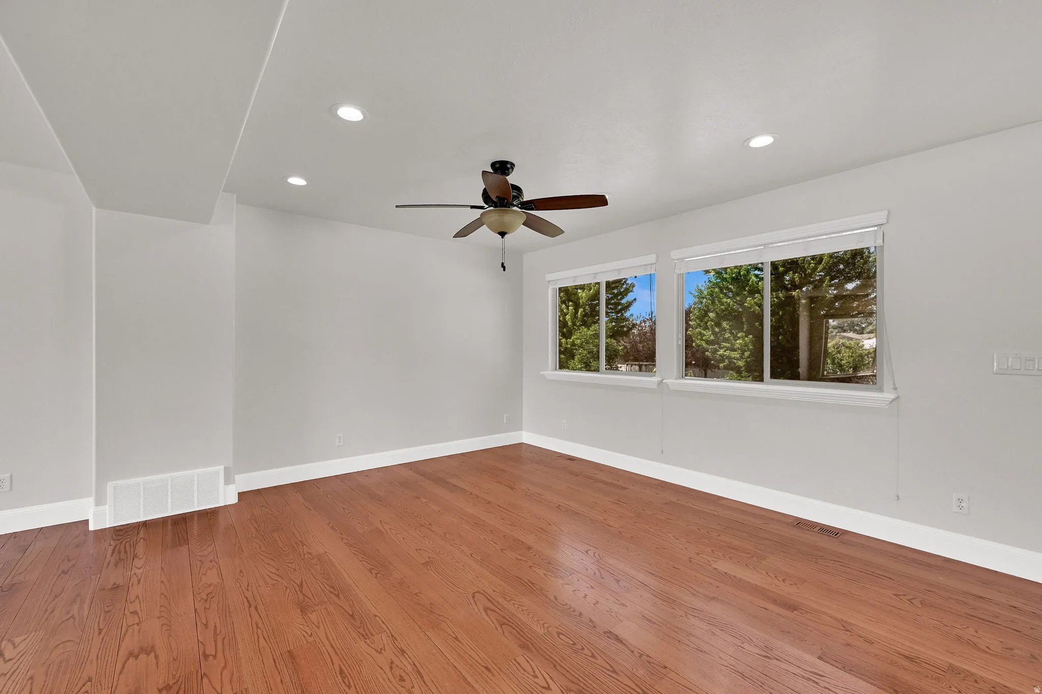 Spacious room featuring rich wood-finish flooring and light-toned walls