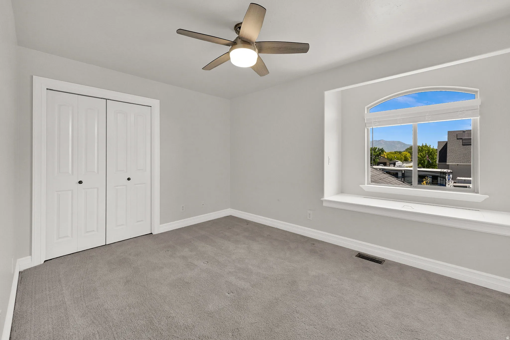 Room with light gray walls, gray carpet, and white baseboards