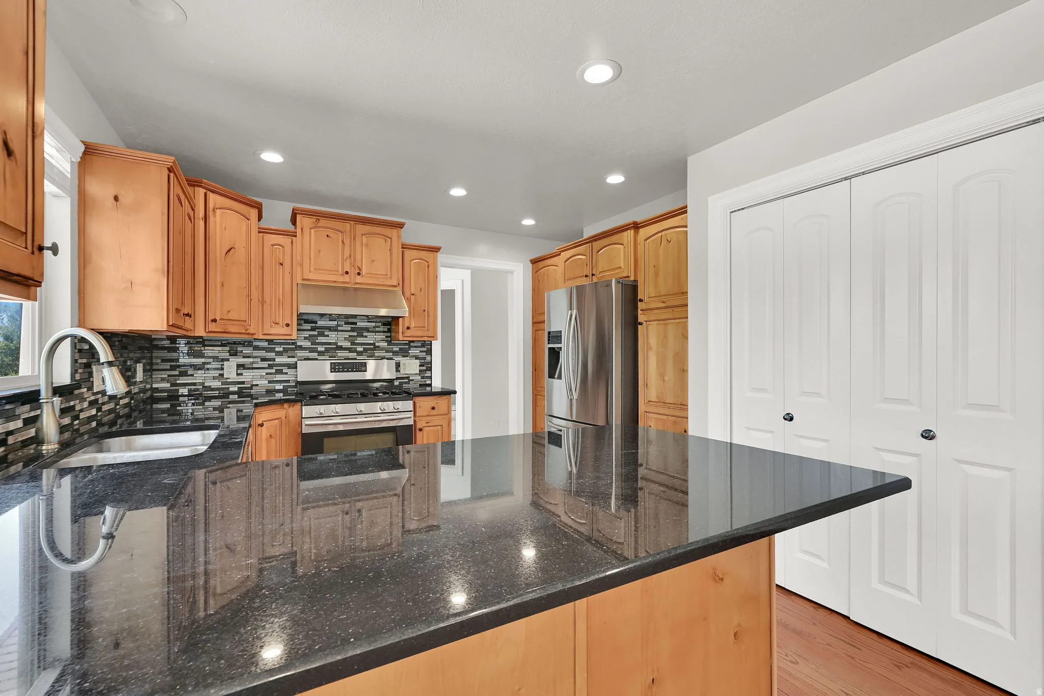 Kitchen featuring granite-look countertops, wood cabinetry, stainless steel appliances, and a mosaic tile backsplash