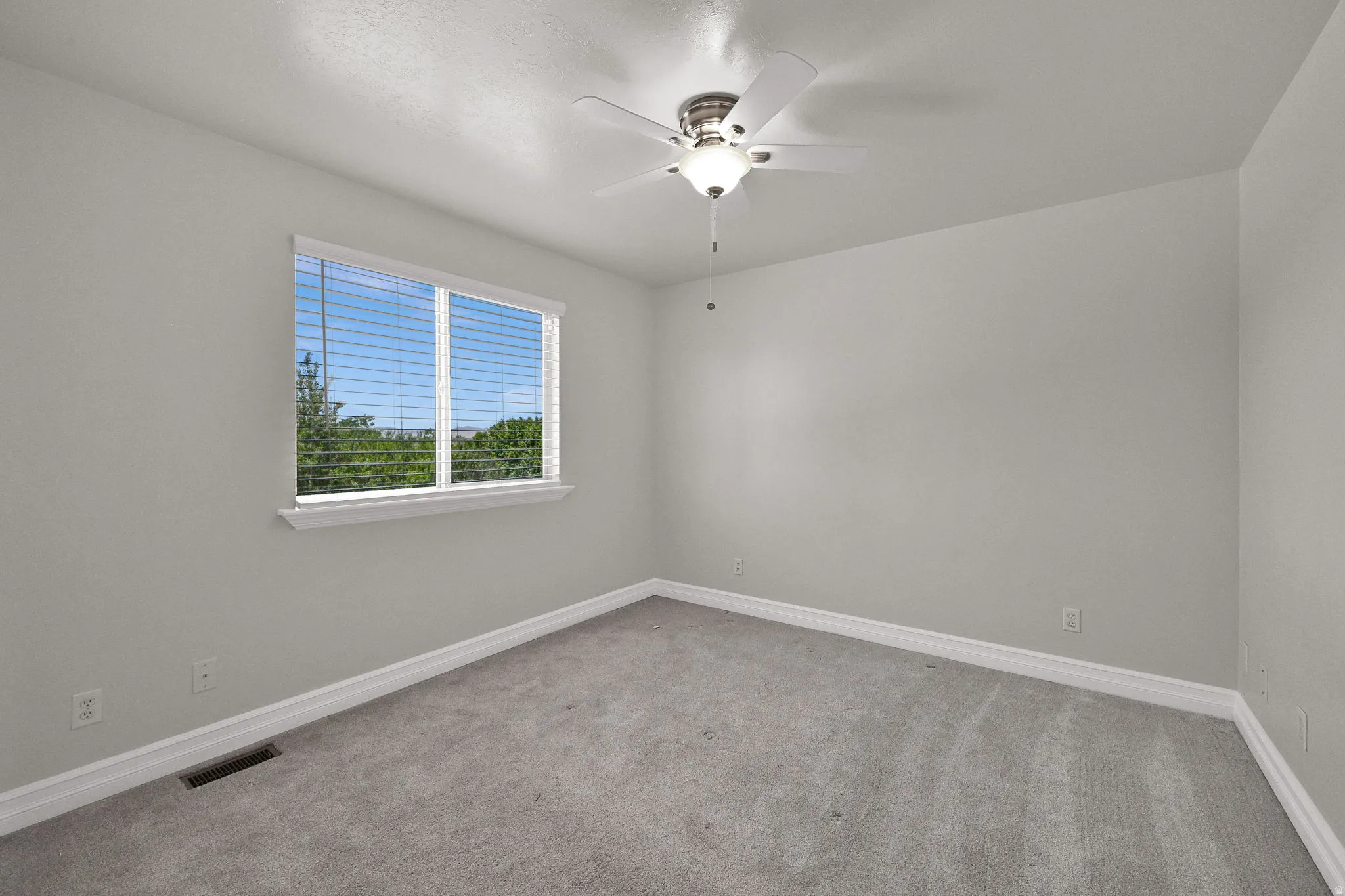 Carpeted interior space with a window featuring horizontal blinds
