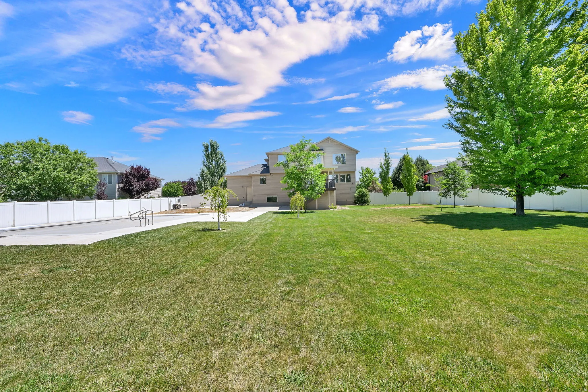 Expansive Half Acre green space featuring a concrete pad, bike racks, and mature trees