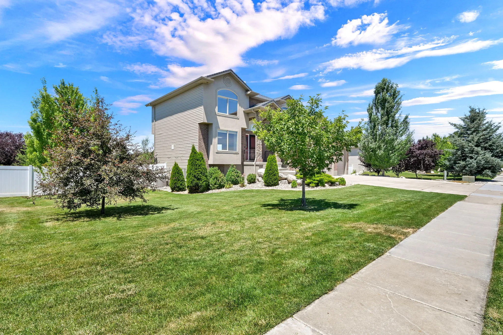 Two-story residence featuring light-colored siding, stone accents, and multiple windows