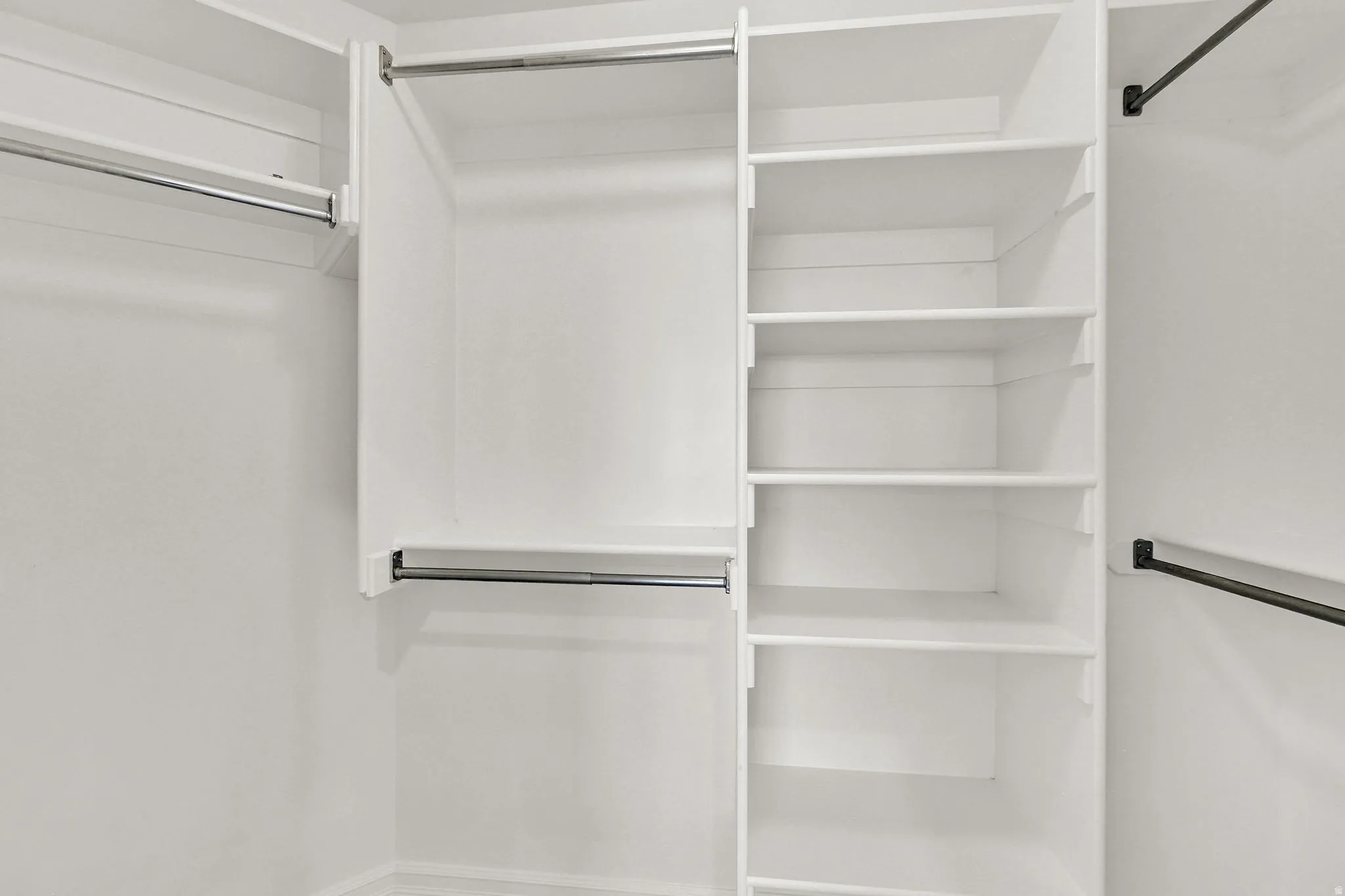 Built-in closet system featuring white shelving, multiple hanging rods, and integrated storage solutions
