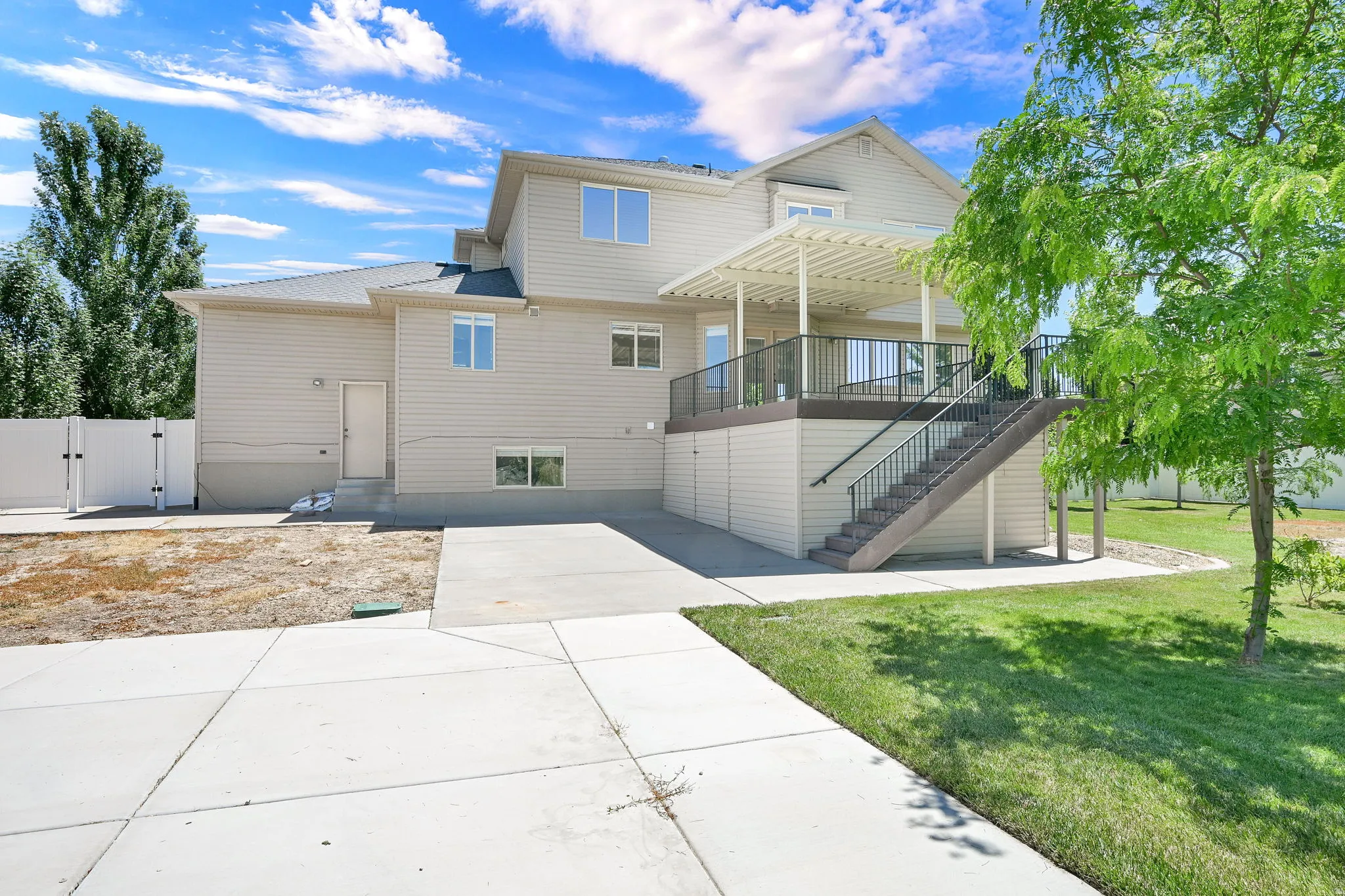Rear exterior featuring an elevated deck with a pergola, exterior staircase, and concrete patio