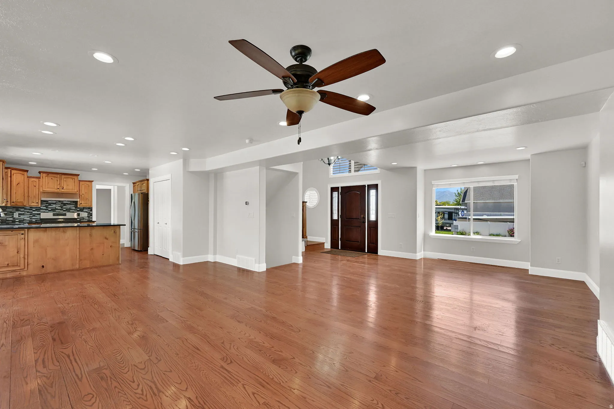 Expansive living area featuring wood-finish flooring and a ceiling fan with integrated lighting