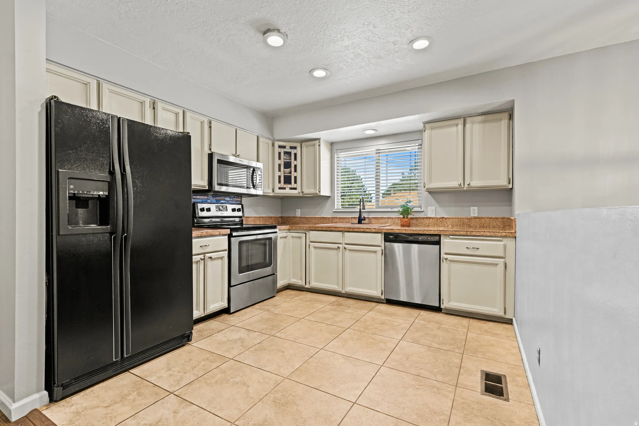 Kitchen featuring light-toned cabinetry, light-toned countertops, and tile flooring