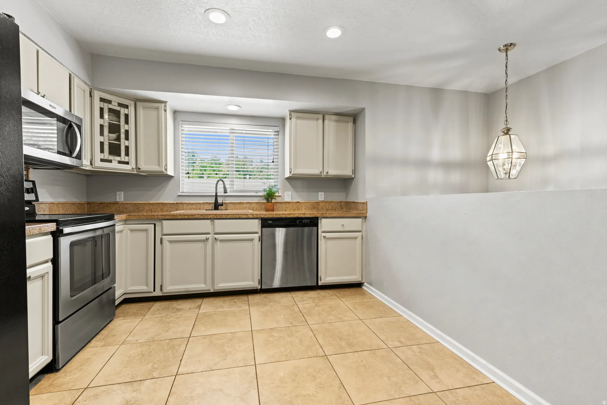 Kitchen featuring beige shaker-style cabinetry, granite-finish countertops, and stainless steel appliances