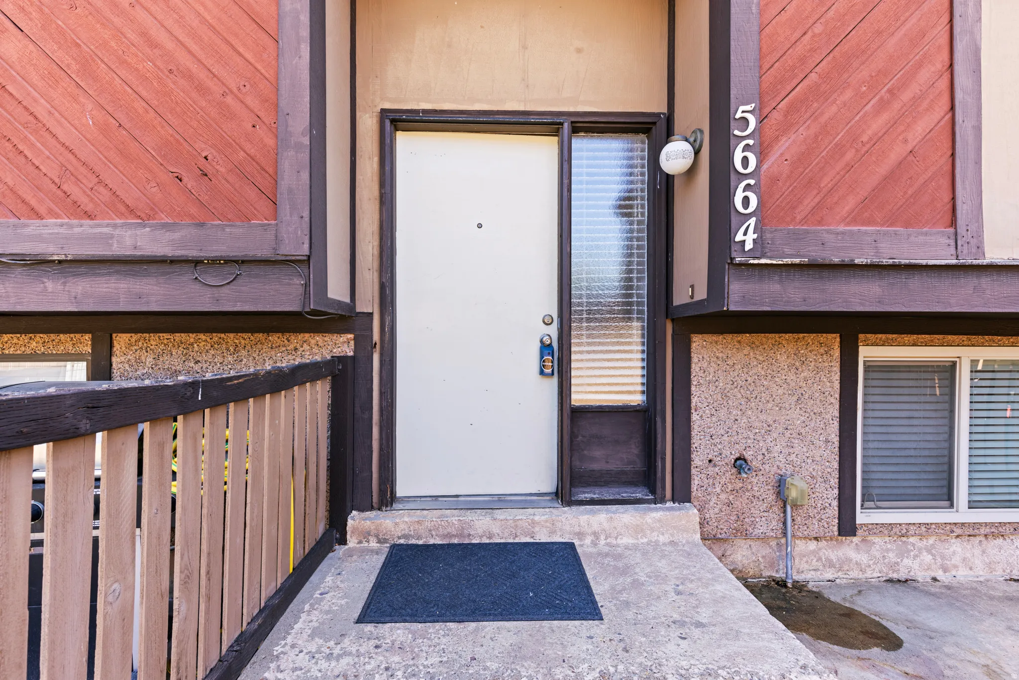 Entryway featuring a white door with sidelight, exterior lighting, and prominent house numbers