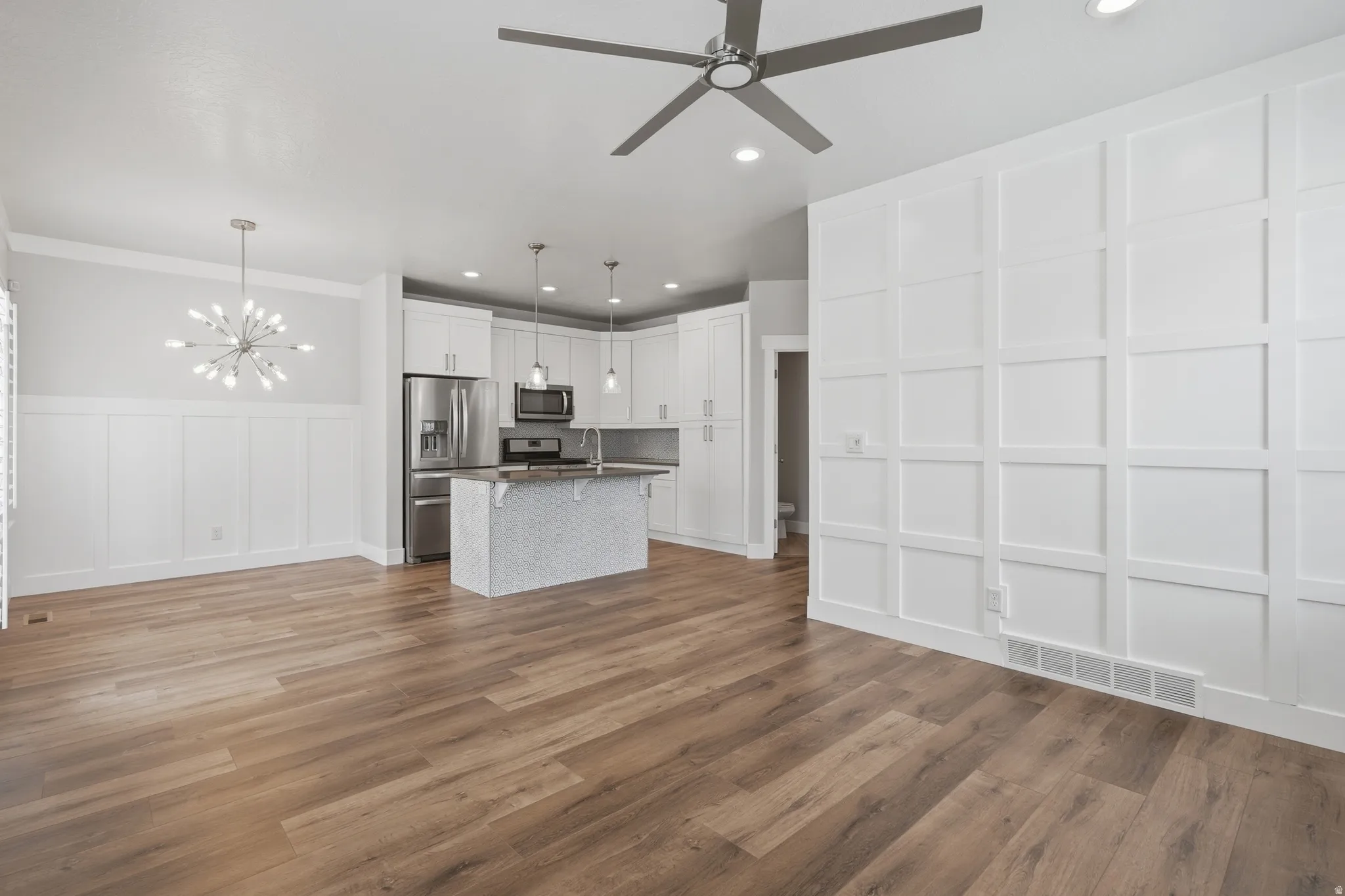 Open-concept living space with wood-finish flooring, a modern sputnik chandelier, and a ceiling fan