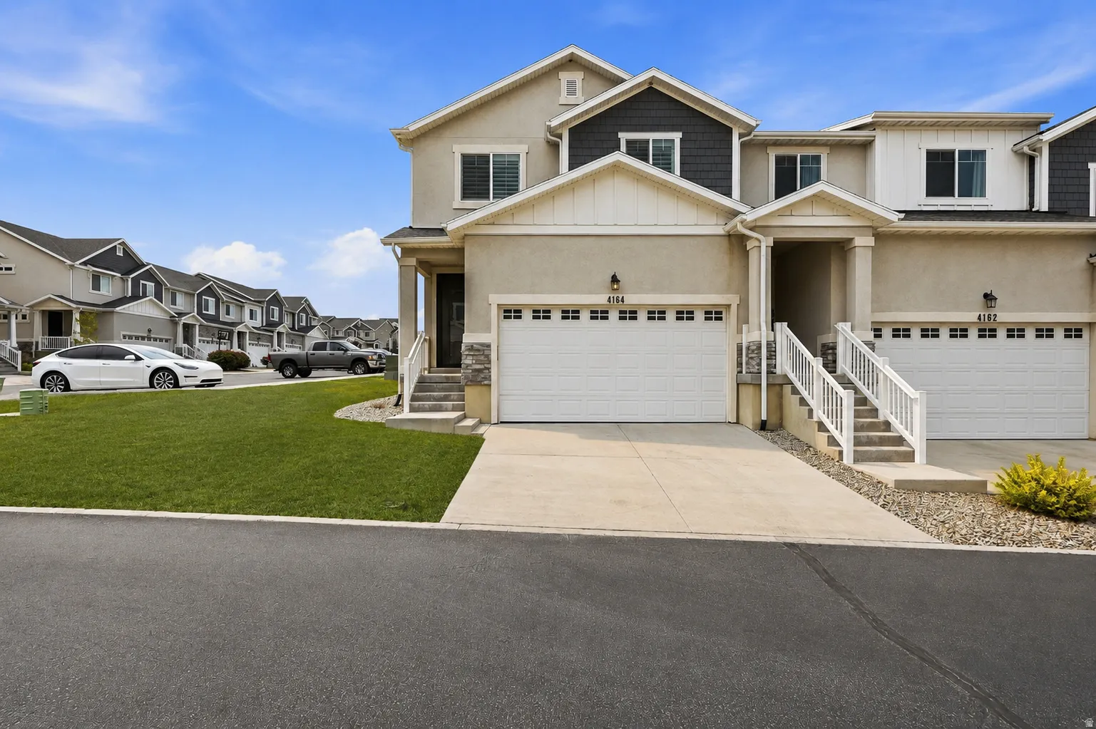 Two-story townhome with a light stucco exterior and dark-shingle gables