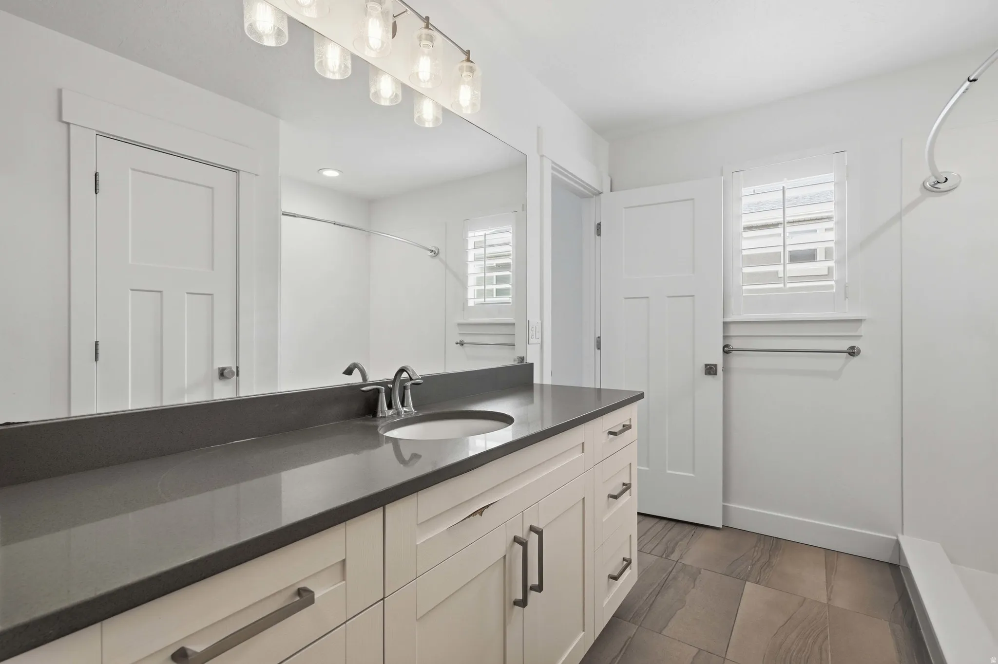 Vanity with a dark countertop, an integrated sink, and brushed nickel fixtures