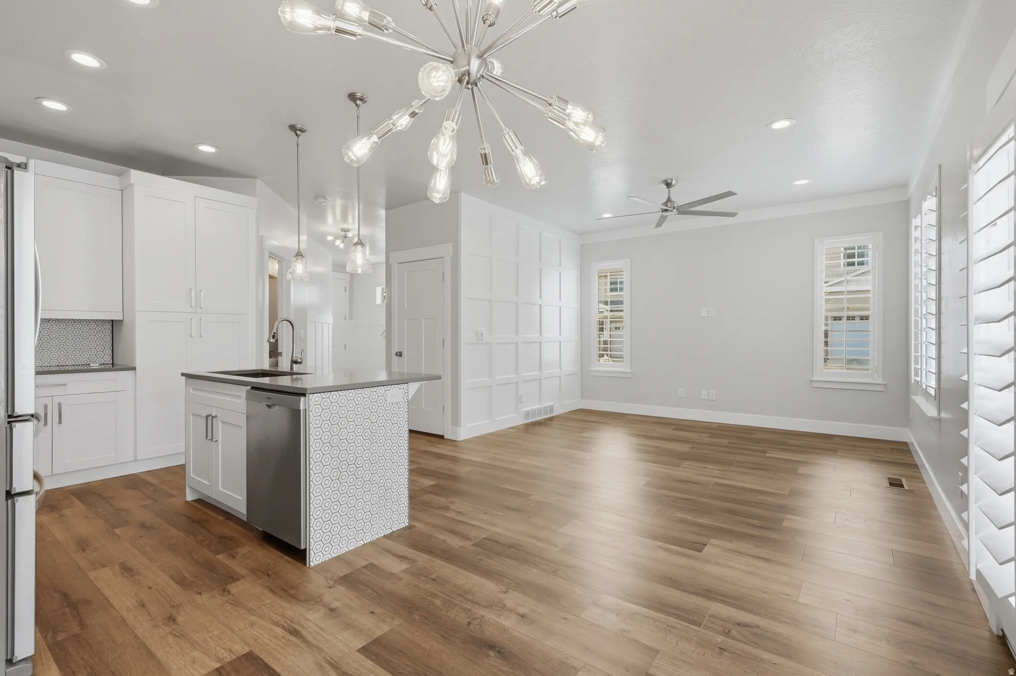 Open-concept living space featuring wood-finish flooring, a contemporary chandelier, and recessed lighting