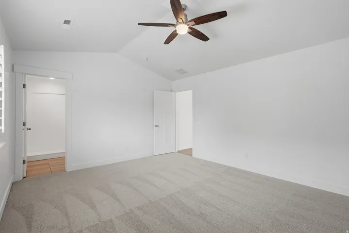 Bright room featuring a vaulted ceiling and a wood-finish ceiling fan