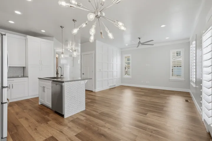 Open-concept living space featuring wood-finish flooring, a contemporary chandelier, and recessed lighting
