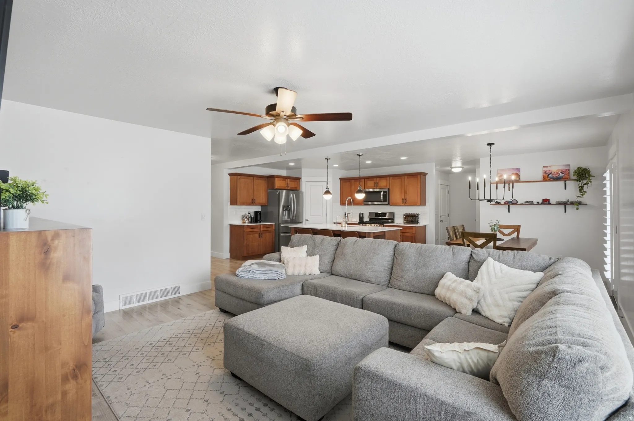 Open-concept living space featuring wood-finish flooring, a ceiling fan, and white walls