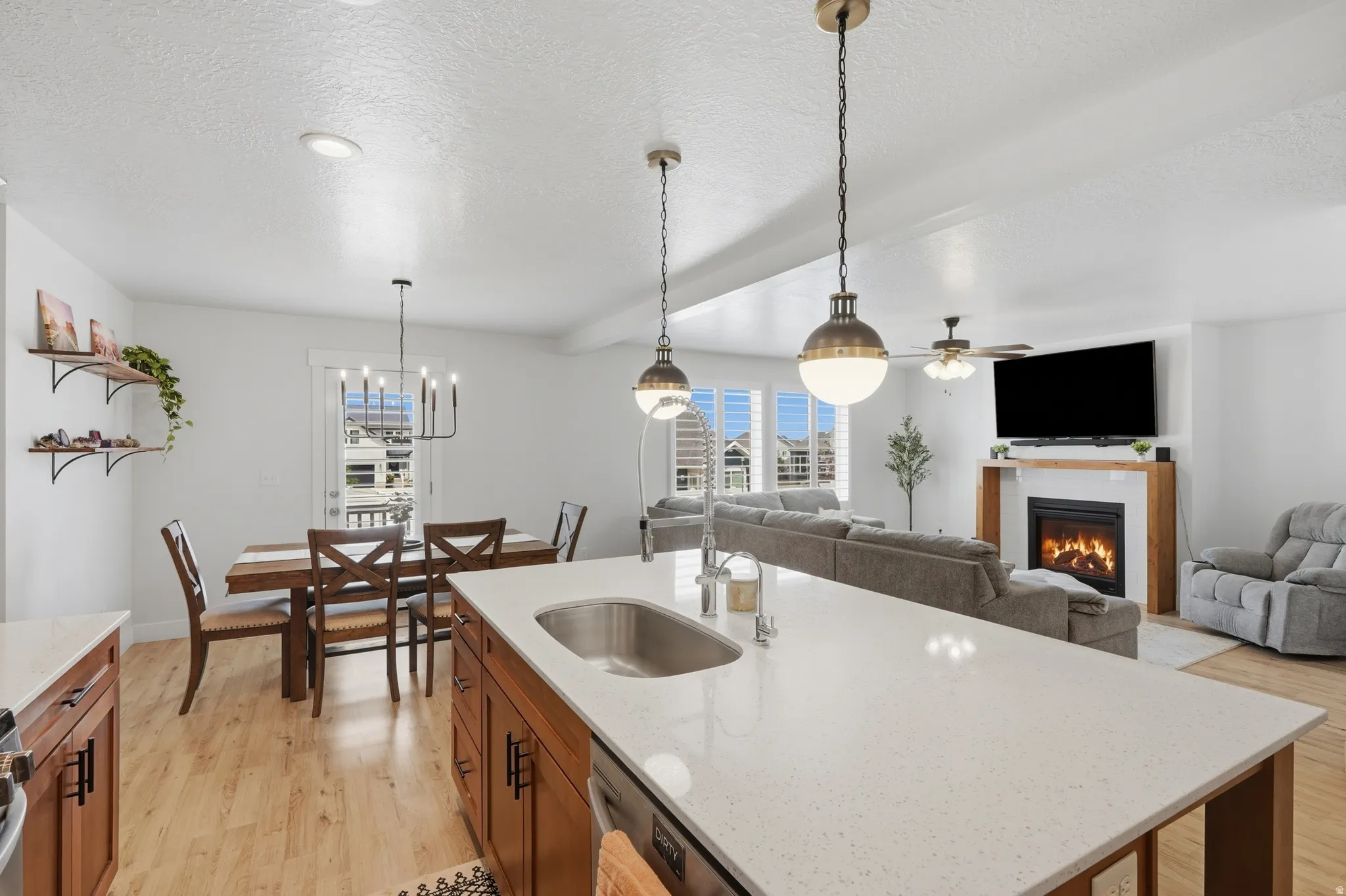 Kitchen island featuring a stainless steel sink, solid surface countertop, and pendant lighting
