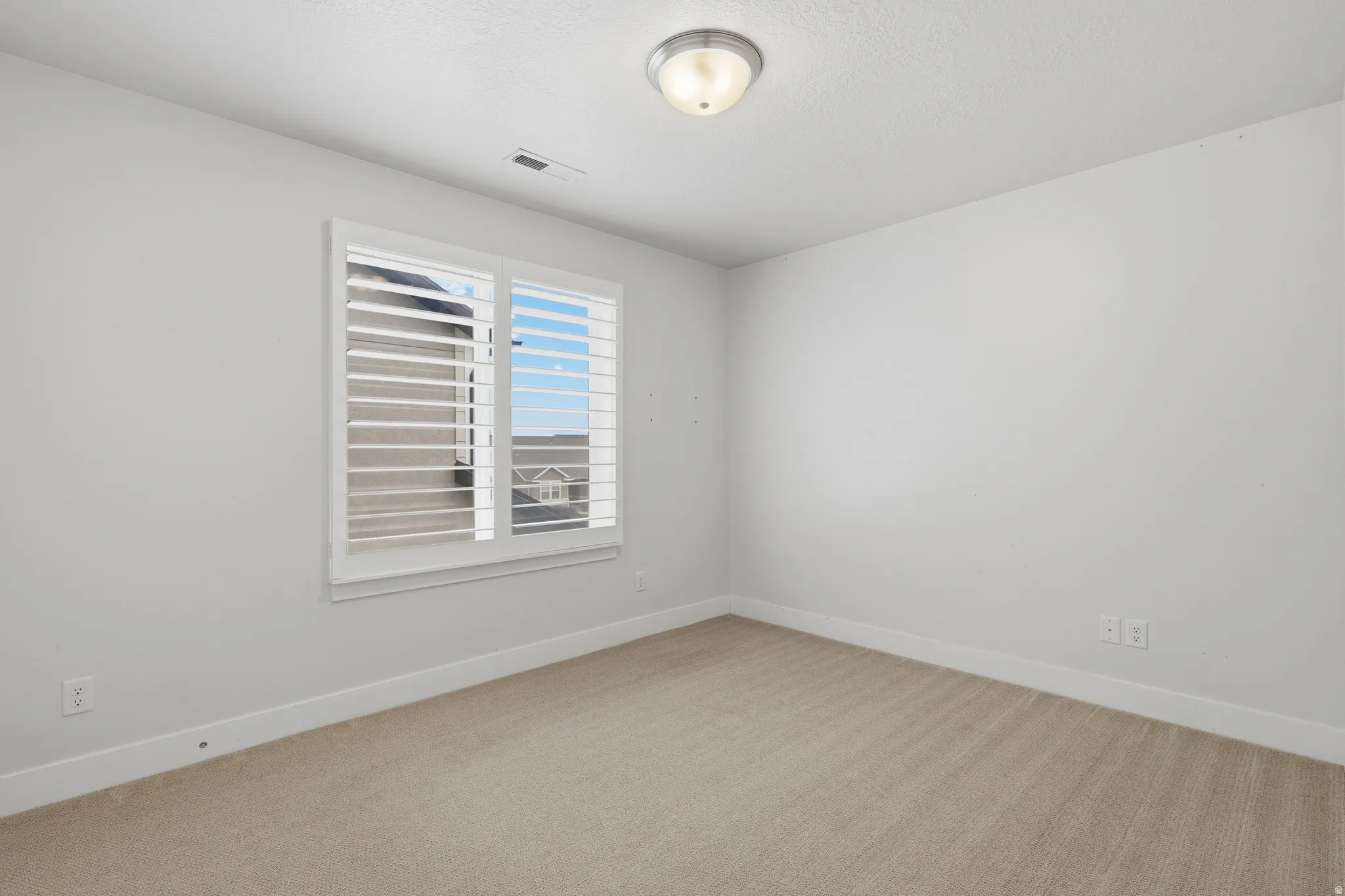 Room featuring a window with white plantation shutters
