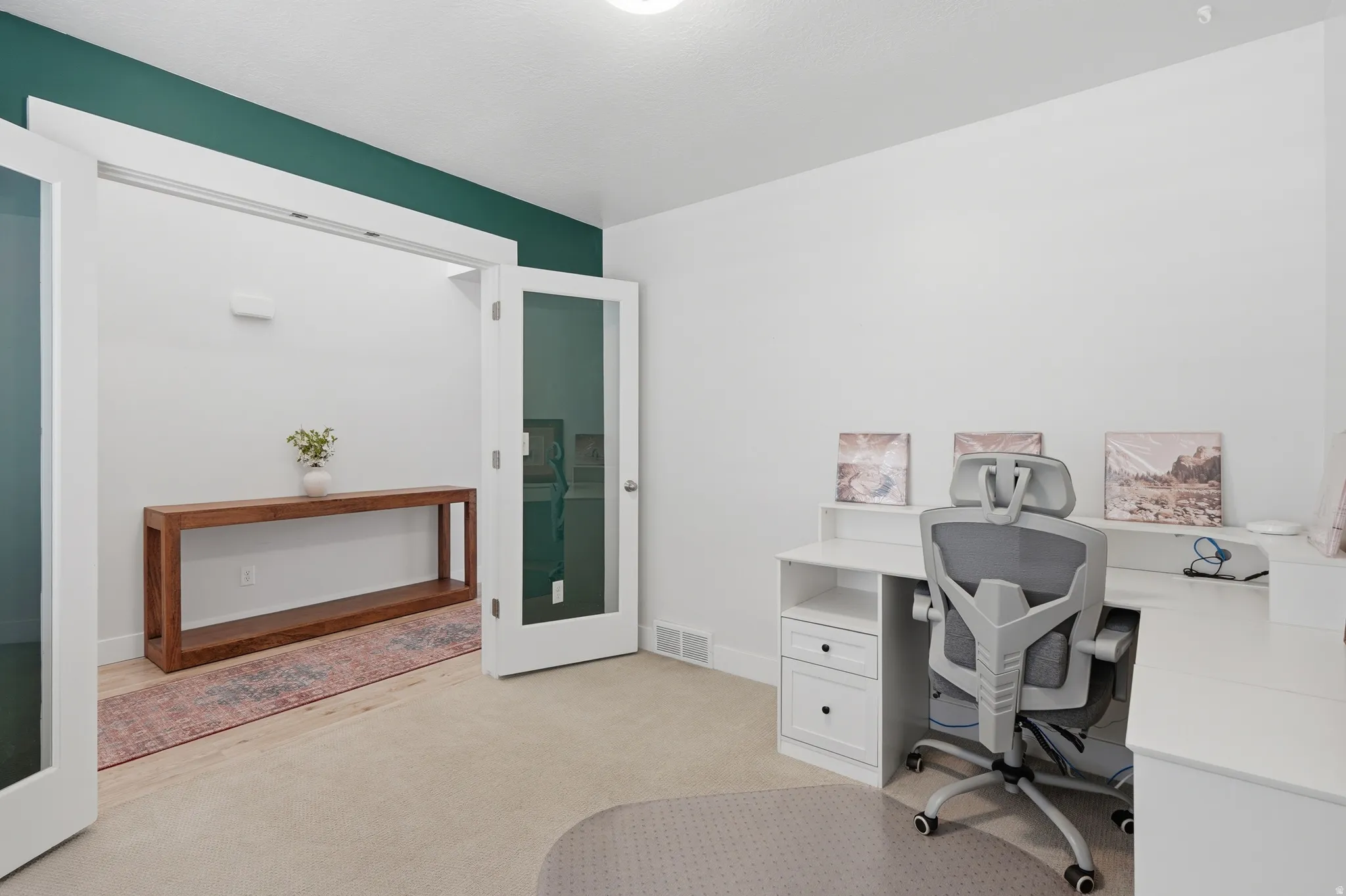 Room with white walls and a deep green accent wall, featuring a carpeted floor, white trim, and a doorway with French doors